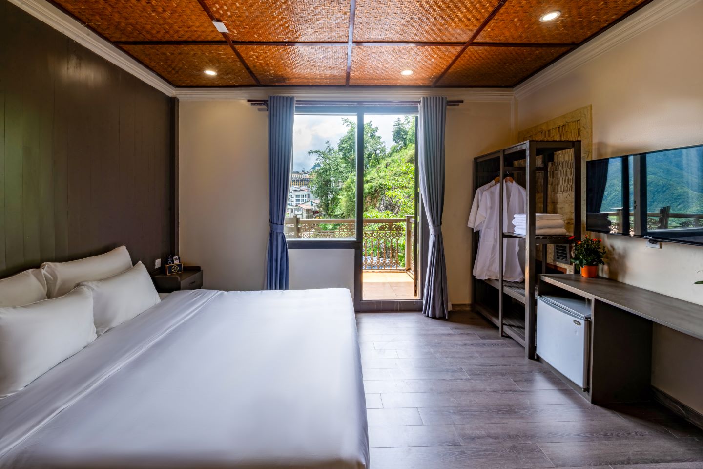 Room opening through full-height doors onto a balcony and green hillside