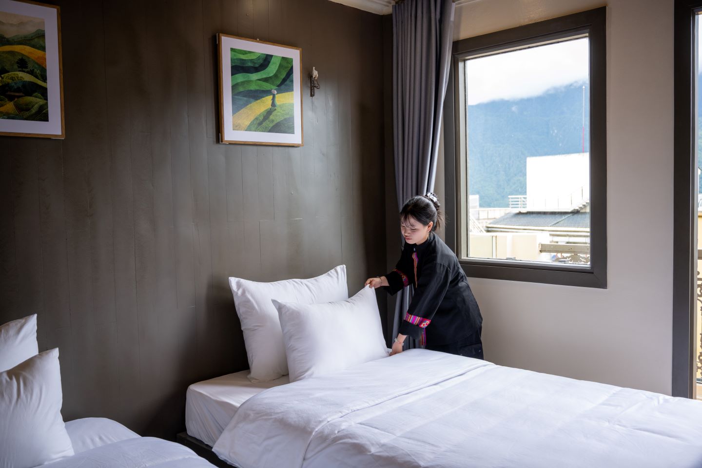 Housekeeping in traditional H'mong dress preparing a room